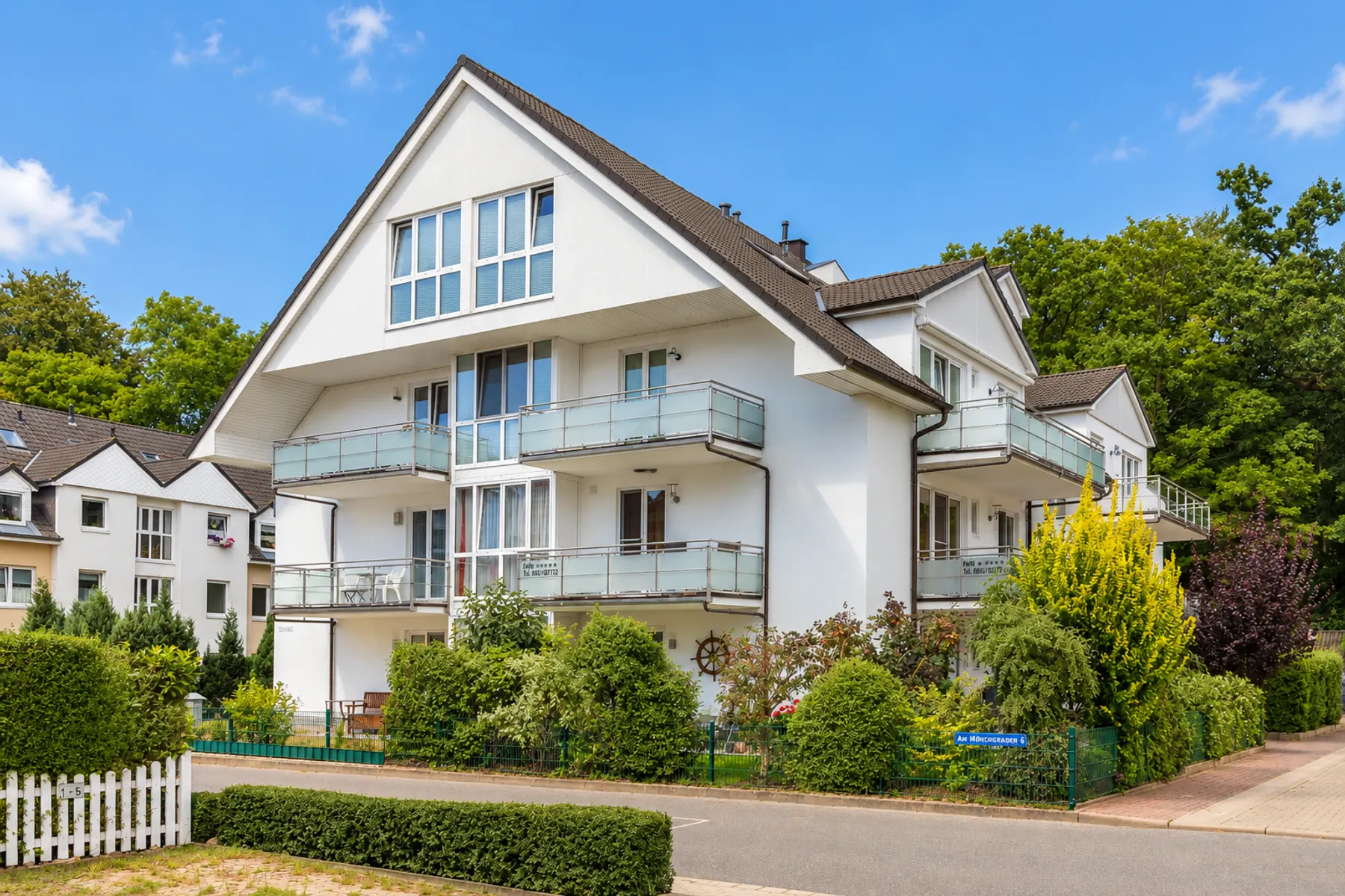 Appartementhaus der Ferienwohnung Helene mit Balkonen hinter grüner Hecke in der Straße Am Mönchgraben