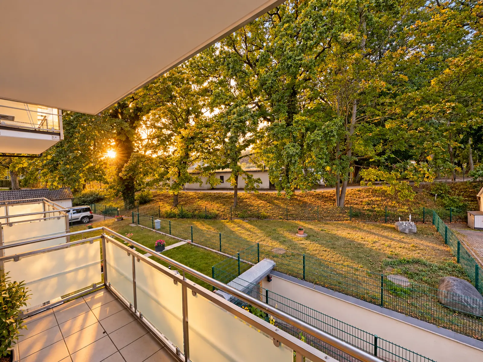 Blick vom Balkon über den Garten und die Bäume im Abendlicht